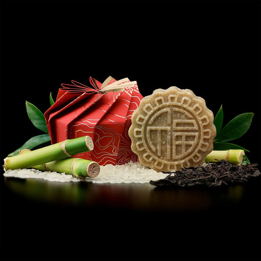 eps bee hive shaped soap with Chinese design surrounded by bamboo, rice grains, tea leaves, and green leaves on black background