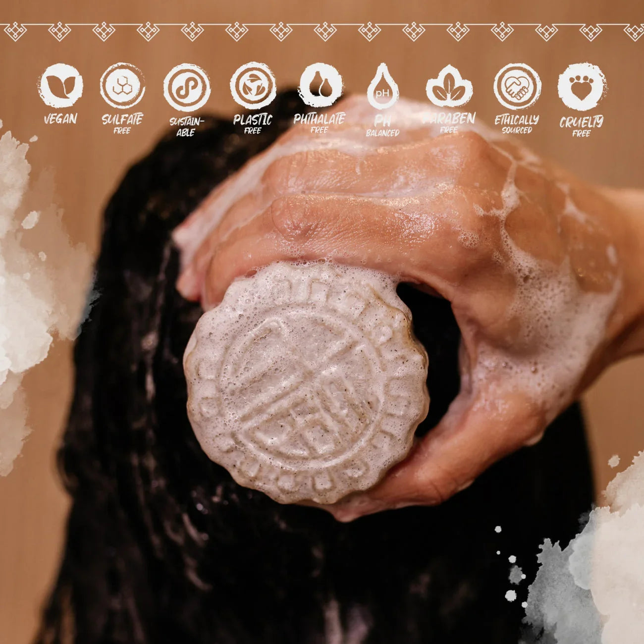 Hand holding a foaming eps bee hive shampoo bar on wet black hair with vegan and sulfate-free icons