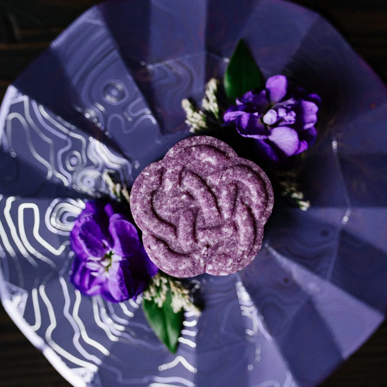 Purple eps bee hive shaped soap on decorative blue plate with purple flowers and green leaves