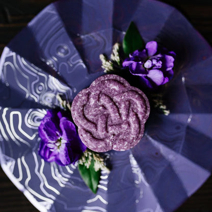 Purple eps bee hive shaped soap on decorative blue plate with purple flowers and green leaves
