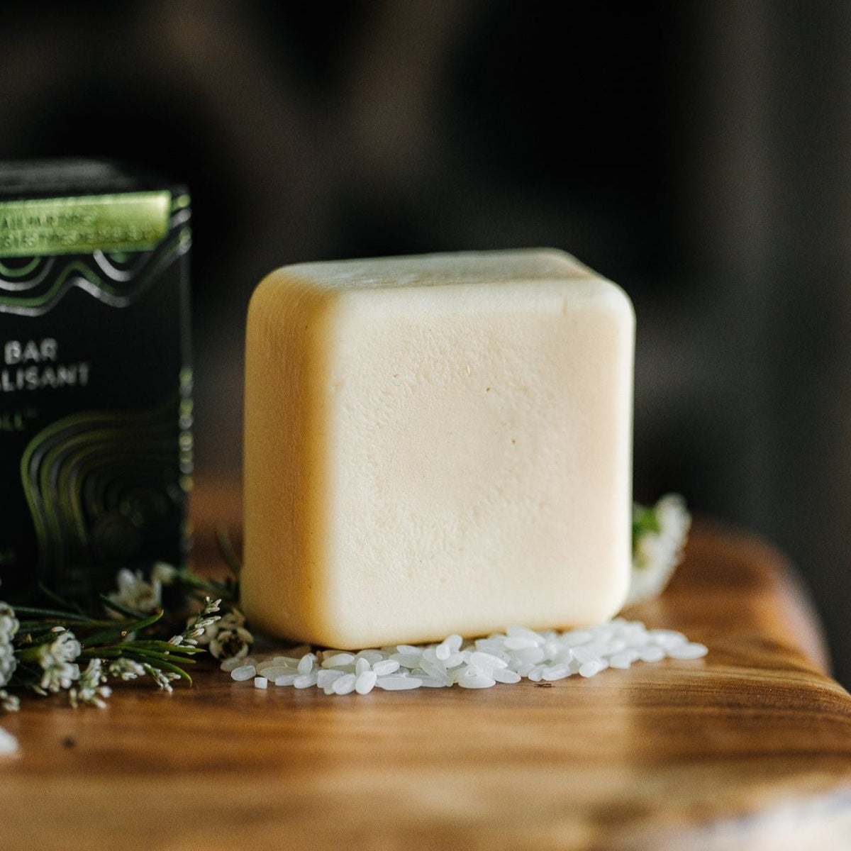 EPS bee hive shaped conditioner bar on wooden surface with white rice grains and small white flowers