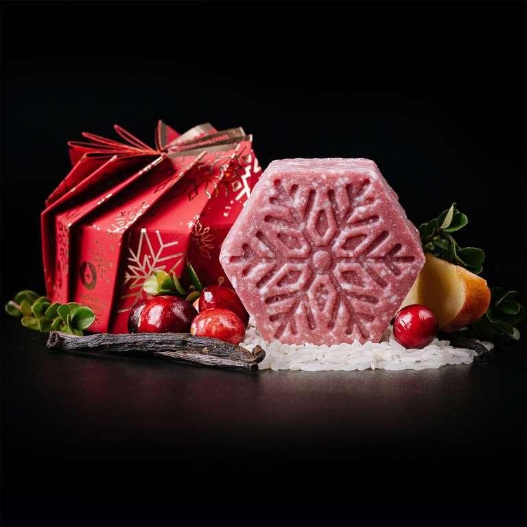 Hexagonal eps bee hive shaped cranberry vanilla shampoo bar with festive red packaging, cranberries, vanilla pod, pear slice, and greenery on black background