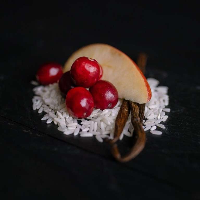 eps bee hive with fresh cranberries, vanilla beans, rice grains, and an apple slice on a dark surface