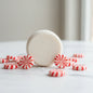 White peppermint shampoo bar surrounded by red and white peppermint candies on marble surface