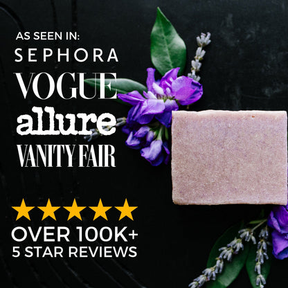 Natural soap bar on black background with purple flowers and green leaves, featured in top lifestyle magazines